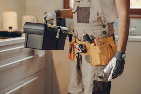 Professional handyman holding tool bag in kitchen