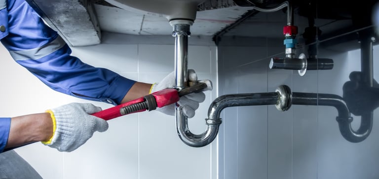 Professional plumber hands holding wrench repairing sink pipe in bathroom