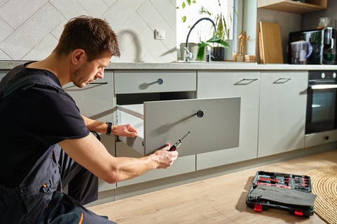 Man assembling kitchen drawer using screwdriver