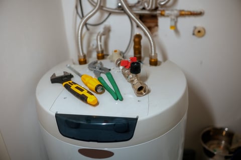 Adjustable wrench screwdriver pliers on water heater with pipes