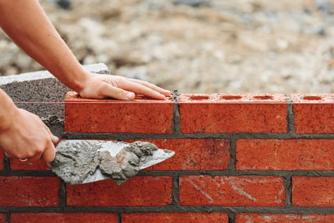 Skilled bricklayer laying bricks for wall construction