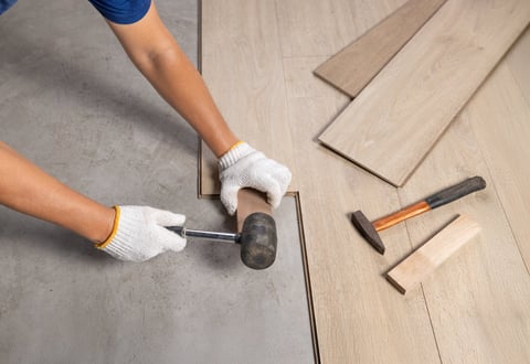 Worker installing interlocking laminate floor during home renovation