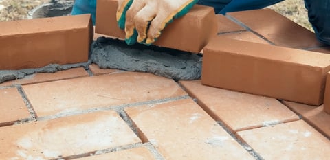 Man building brick wall with brick on solution