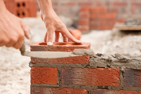 Worker placing bricks with precise movement on construction site