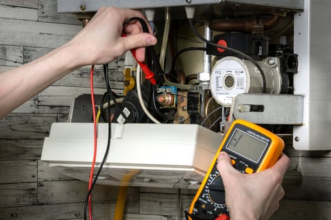 Young man repairing electric water heating boiler