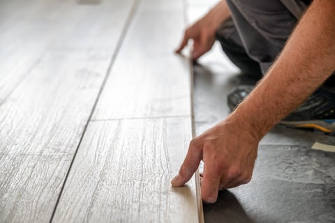 Installation of new laminate floating floor - hands of worker