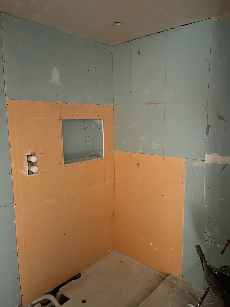 Unfinished bathroom shower enclosure with orange drywall, gray cement board, and a recessed niche with built-in fixture cutout