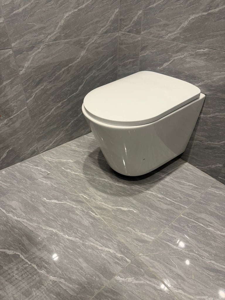 Modern white wall-hung toilet with closed lid in a gray marble bathroom