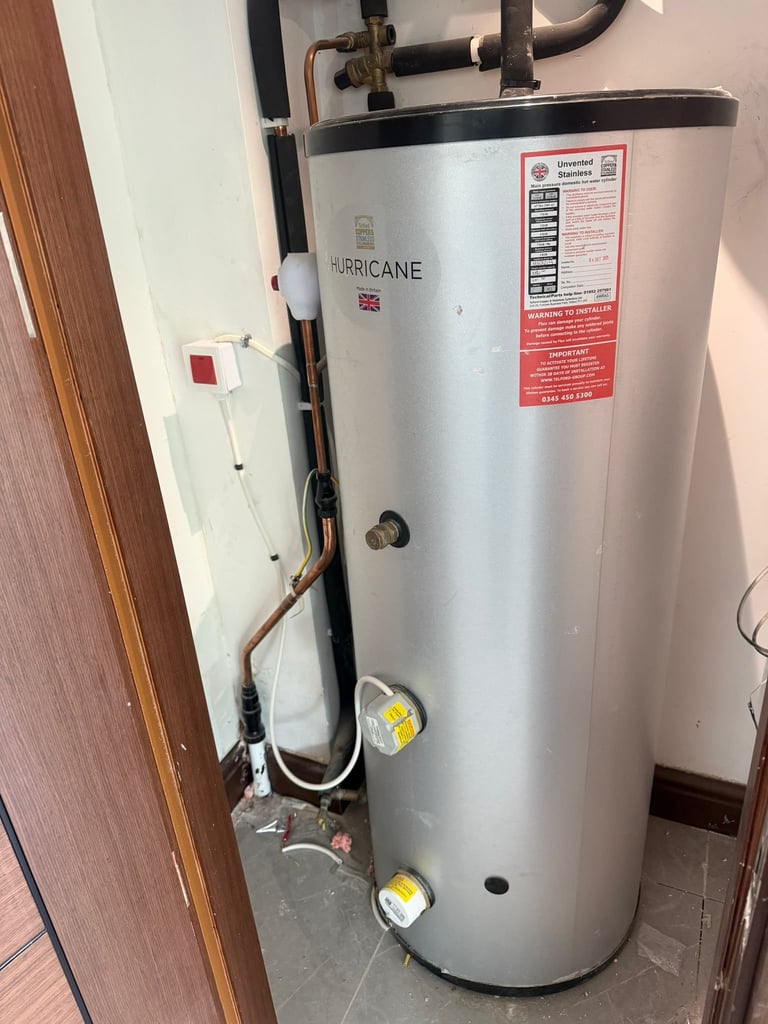 A Hurricane brand water heater tank positioned in a utility room with pipes, electrical connections, and warning labels visible