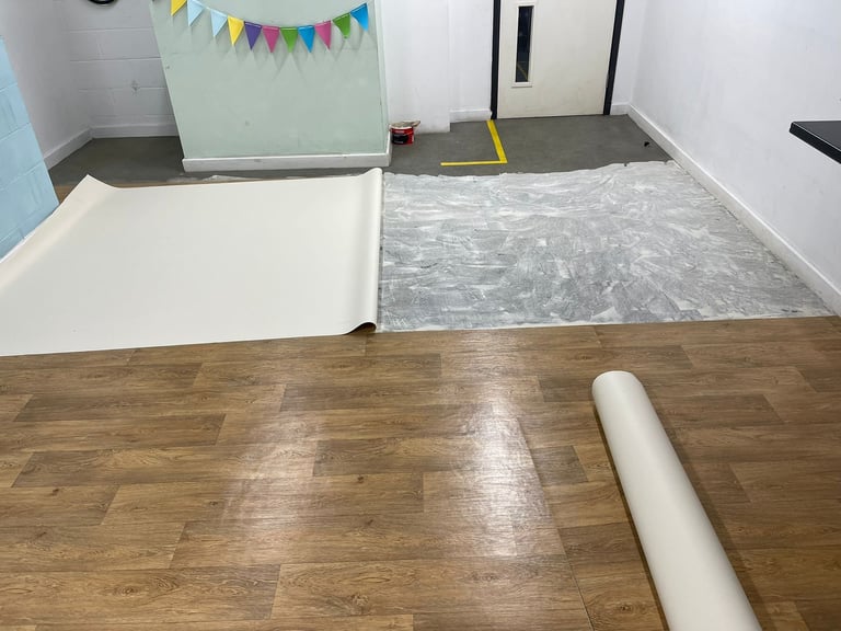 Interior room with wood flooring showing protective plastic and paper coverings laid out during renovation or construction work
