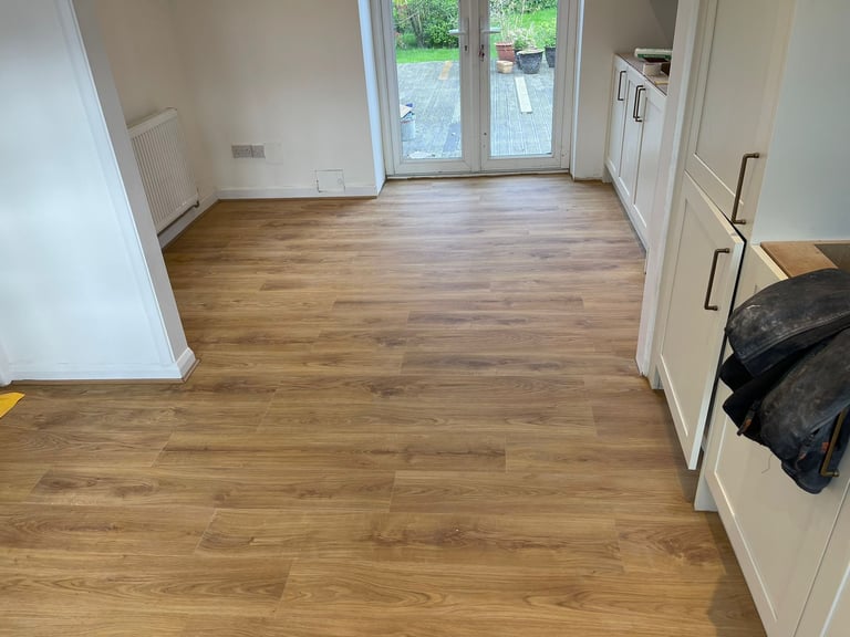 Empty room with wooden flooring, white walls, glass patio doors, and built-in cabinets on the right side