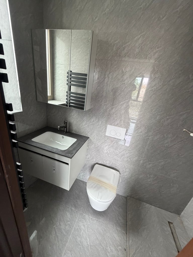 Modern gray bathroom interior with white toilet, wall-mounted sink, mirror cabinet, and heated towel rack