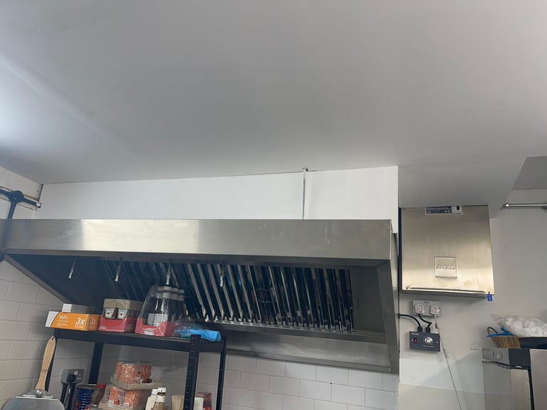Commercial kitchen exhaust hood with ductwork and ventilation system mounted above cooking equipment