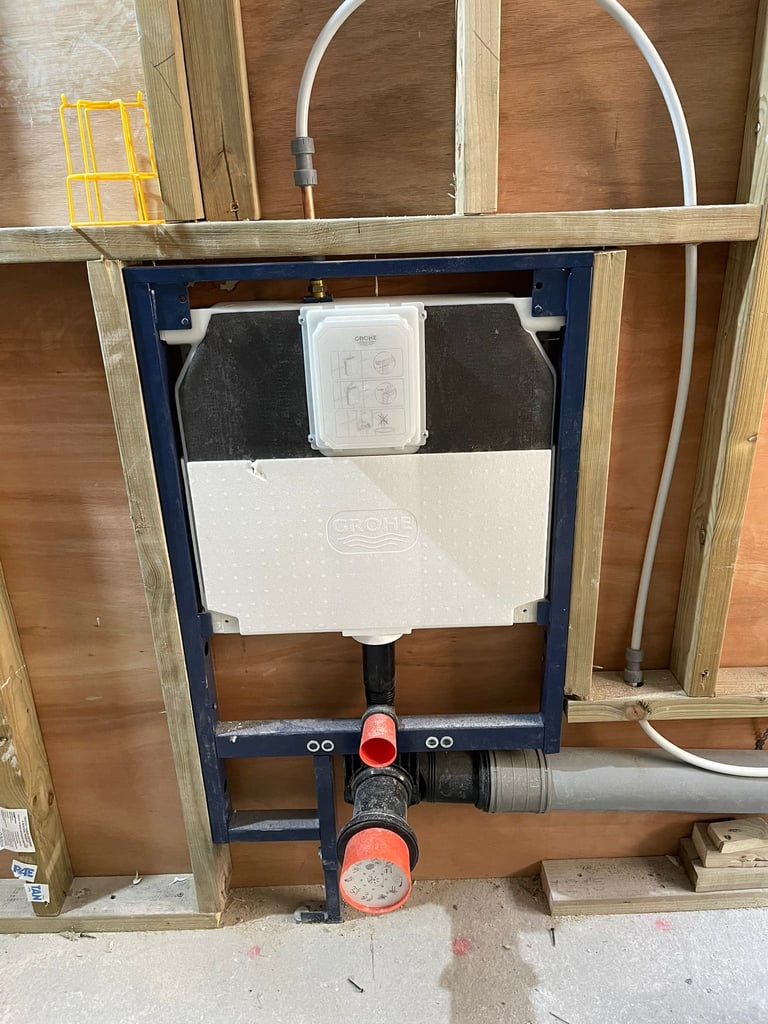 Wall-mounted toilet tank frame with white porcelain cistern, black water supply lines, and red shut-off valve during installation