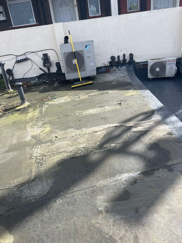 HVAC units and equipment on concrete pad against white building wall with yellow caution bar