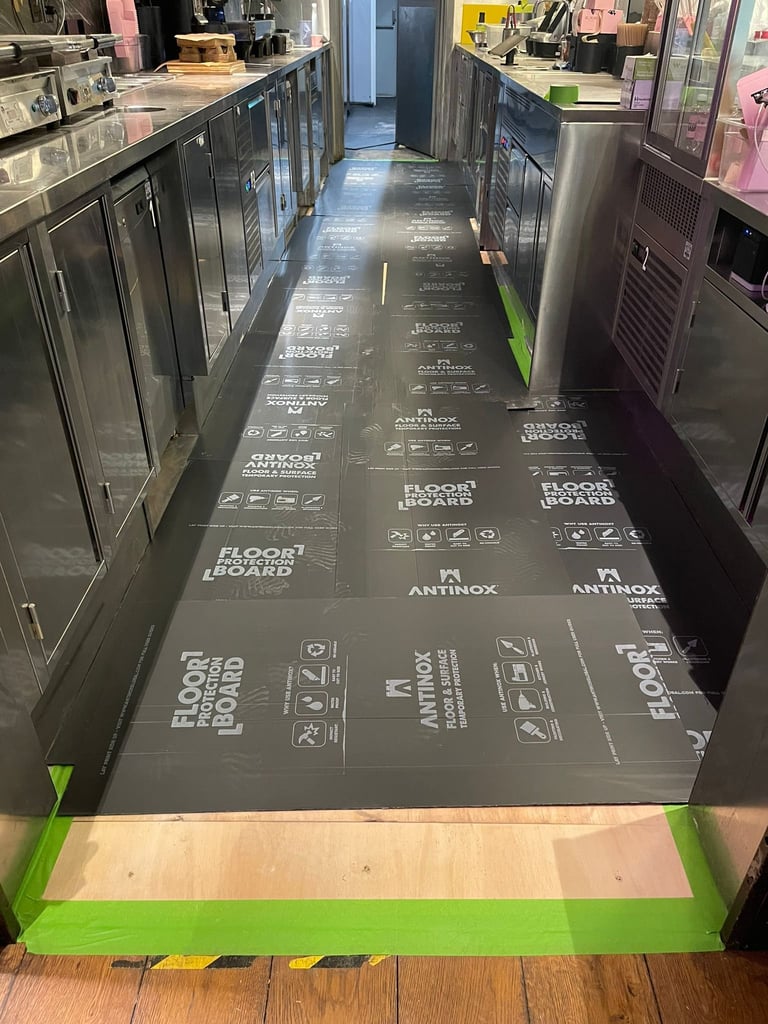 Commercial kitchen floor with protective flooring installation showing product labels and branding during renovation or installation process