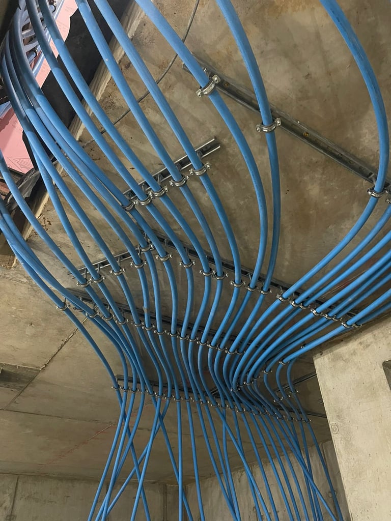 Blue electrical conduit pipes bundled together with metal clamps mounted on concrete walls and ceiling