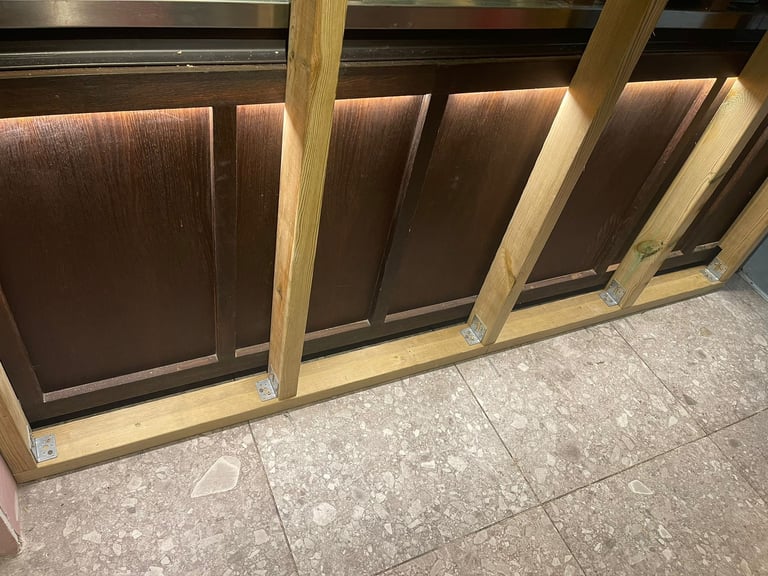 Wooden frame with dark panels and metal top rail resting on tiled floor