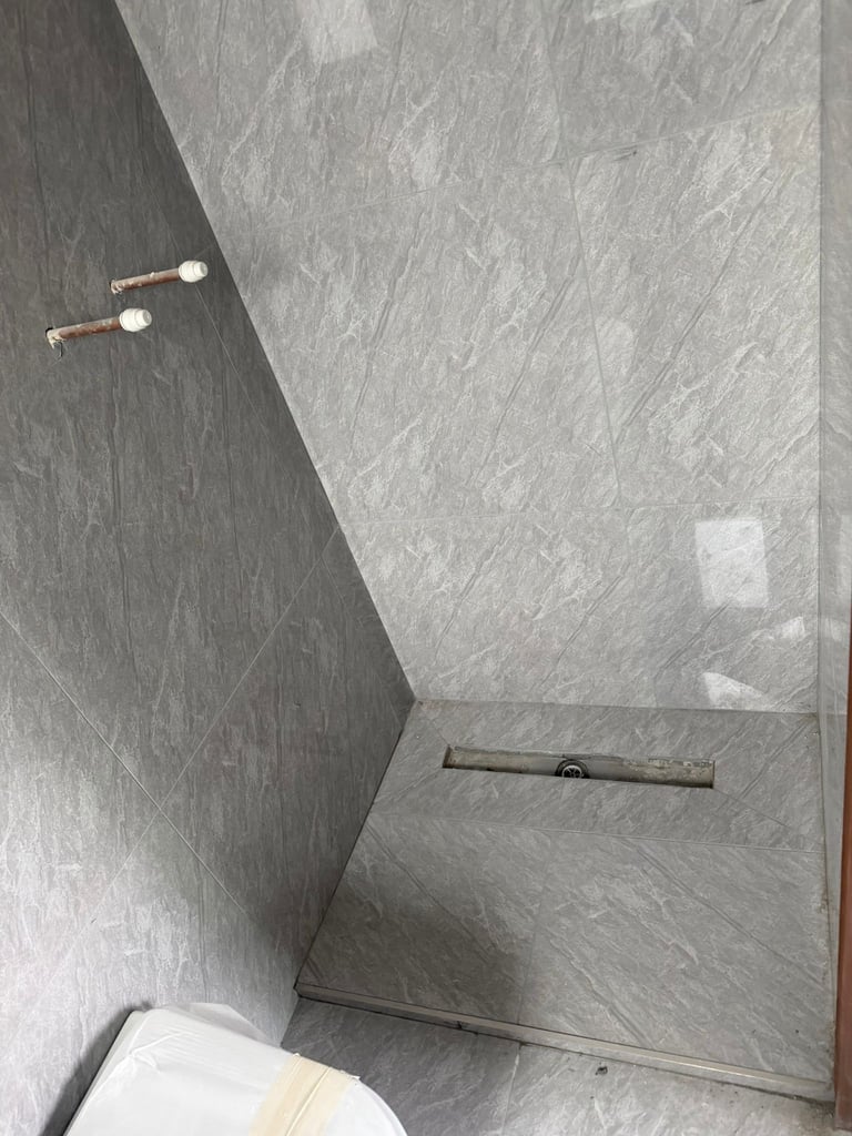 Modern gray tile shower interior with overhead rain showerhead and floor drain, viewed from above