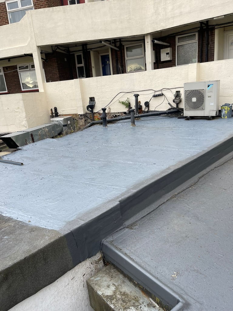 Rooftop terrace with waterproofing membrane, mechanical equipment, and air conditioning unit against a residential building
